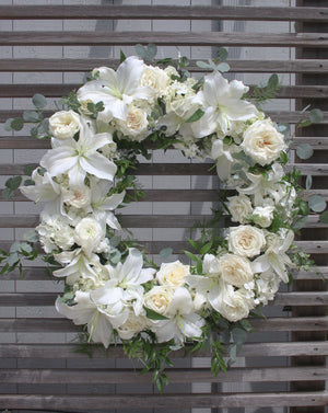 A round funeral wreath with white flowers.
