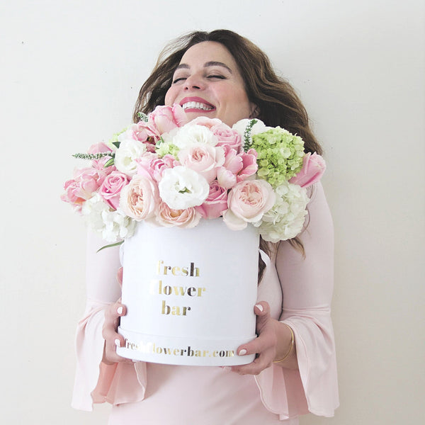 A photo of a smiling woman holding a large flower arrangement.