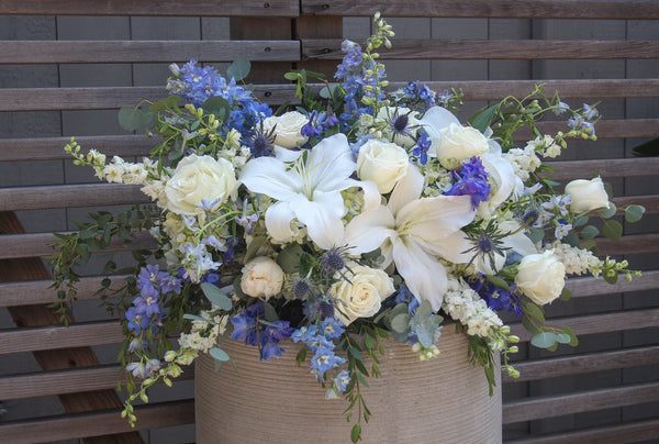 A large funeral spray with white and blue flowers.