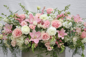 A photo of a Full Casket Cover made with white and pale pink flowers.