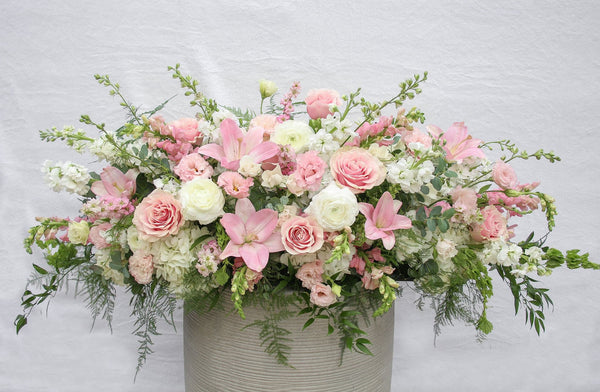 A photo of a Full Casket Cover made with white and pale pink flowers.