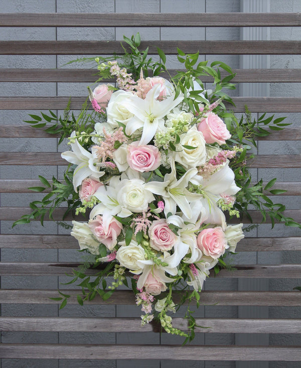 A funeral spray with white and pale pink flowers.