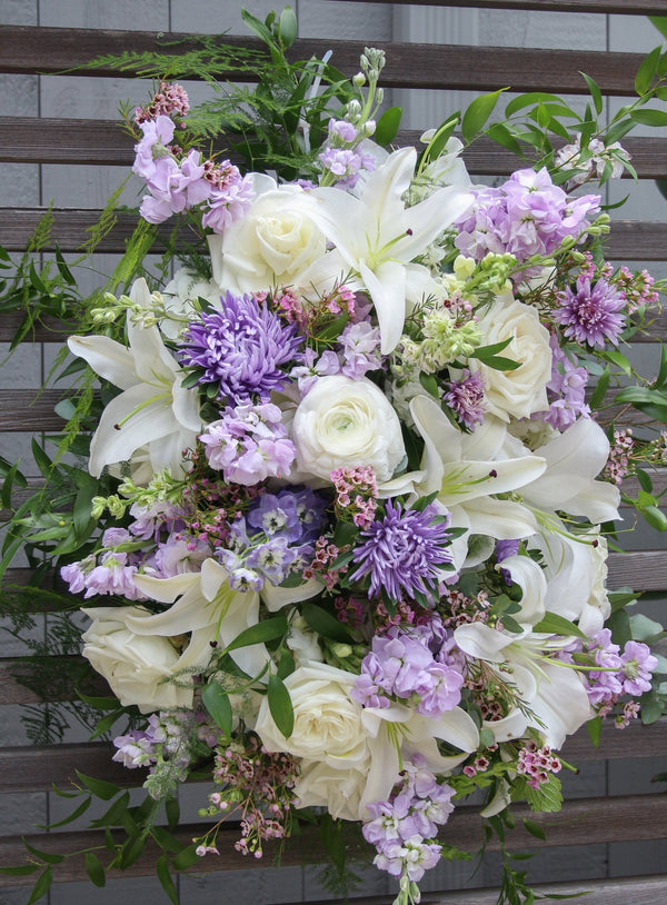 A funeral spray with white and pale purple flowers.