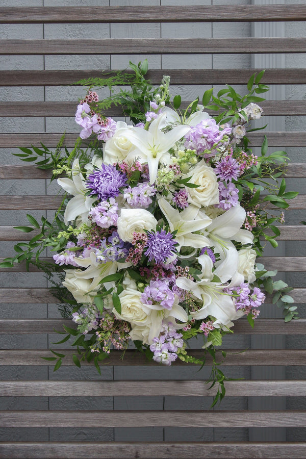 A funeral spray with white and pale purple flowers.