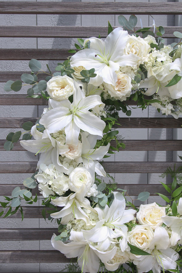A round funeral wreath with white flowers.