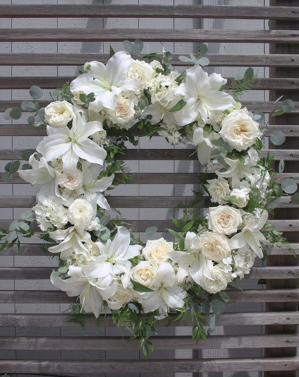 A round funeral wreath with white flowers.